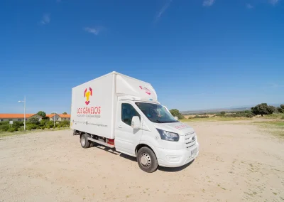 Camión blanco de Mudanzas y Guardamuebles Los Gemelos estacionado en campo abierto.