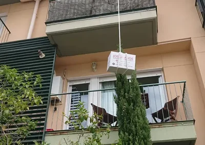 Operario de Los Gemelos bajando caja por un balcón con un sistema de poleas.