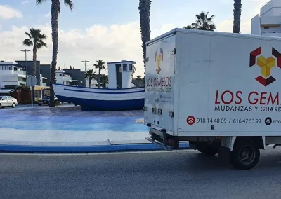 Furgoneta de Los Gemelos aparcada frente a un puerto marítimo.