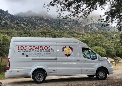 Furgoneta de Mudanzas y Guardamuebles Los Gemelos en una carretera rural con vistas montañosas.