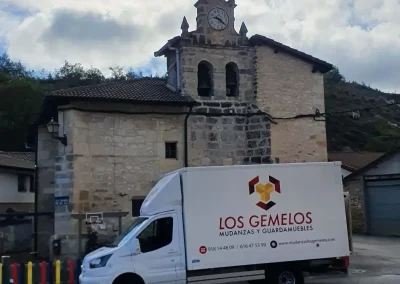 Furgoneta de Los Gemelos estacionada frente a una histórica iglesia de pueblo.