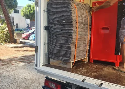 : "Mantas protectoras sujetas con correas naranjas en la parte trasera de un camión de mudanzas de Los Gemelos.